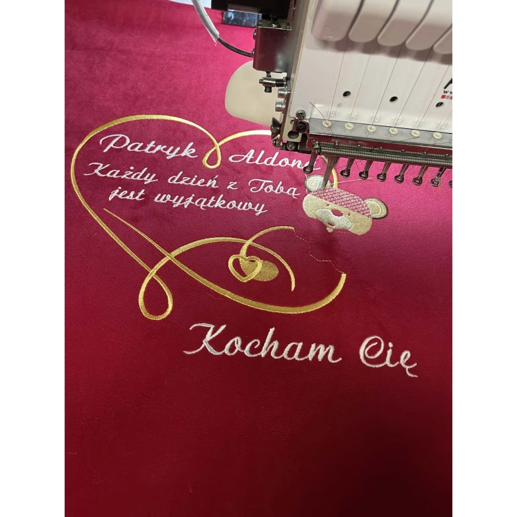 Haftowanie czerwonej poduszki z imionami Patryk i Aldona oraz dedykacją Kocham Cię